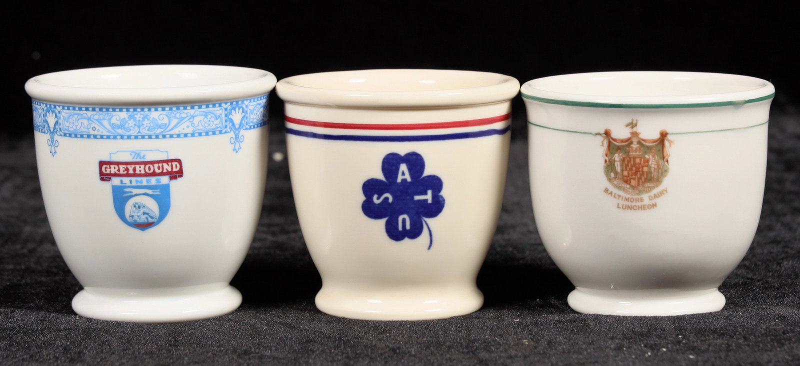 Egg Cup Trio [197062]: 3 vintage egg cups. Red and blue stripe, was a US Army transportation piece by Old Ivory, c. 1942. Green stripe Baltimore Dairy Luncheon, by Lamberton China, small base chip. Blue The Greyhound Line,