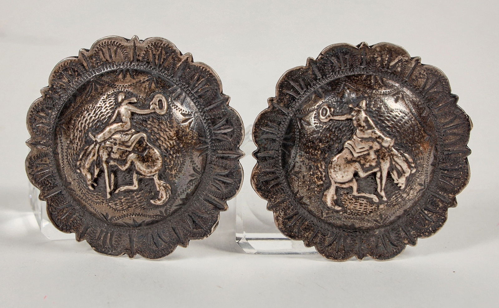Vintage Silver Conchos [201882]: Two vintage silver conchos, unmarked, with bucking bronco and rider on each. Total weight 48 grams; 47 mm each.^Date: Country (if not USA): State: City: Provenance: