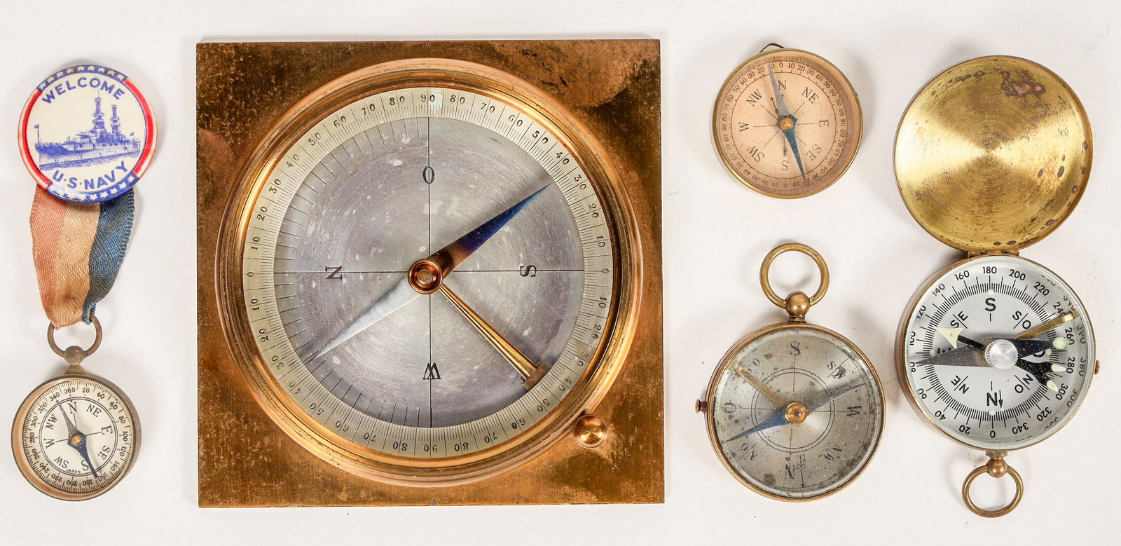 Miscellaneous Compasses (6) [202898]: This group has six miscellaneous compasses. Only one is identified as a Marbles pin-on hunting compass. There is a large map reading compass where east is marked as "O" indicating a German or Norwegia