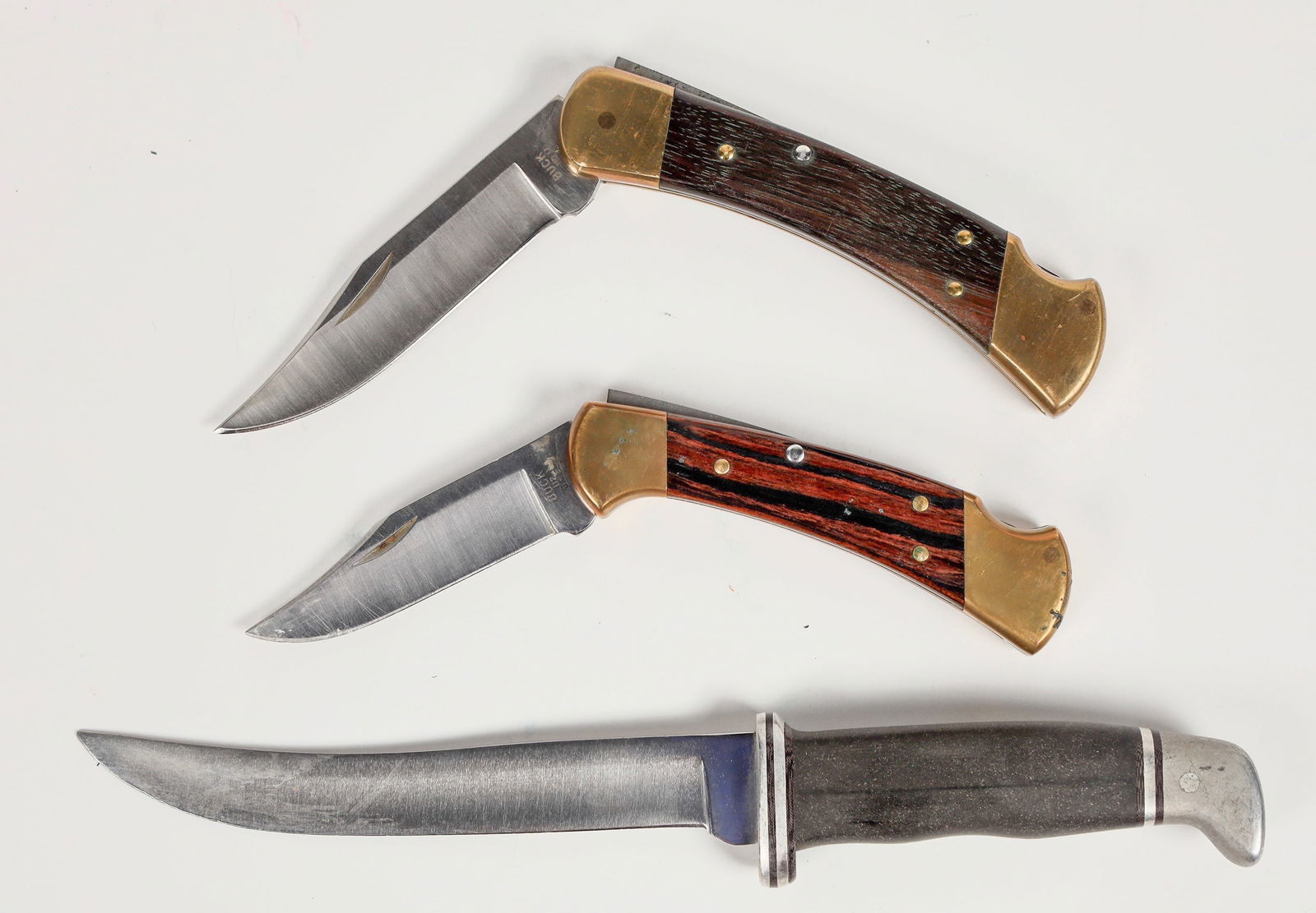 Buck Knives (3) [202210]: Instant Buck knife collection with : a Buck 110 made in 1998 very good condition, a Buck 112 made in 1994, in good used condition, a Buck 121 fishing knife in good condition with sheath. There are no