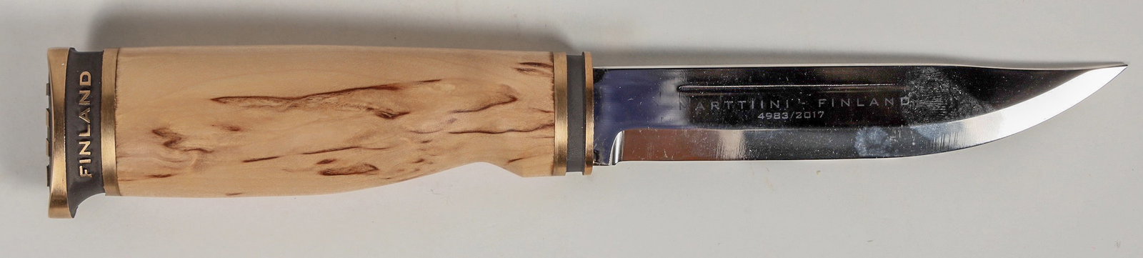 Marttiini-Suomi Finnish 100th Anniversary Sheath Knife 1917-2017 [201019]: This is Marttiini-Suomi 100th anniversary sheath knife made in Finland. These knives are noted for their durability. At 8.75 in. ( 222 MM) with a stainless blade, bronze ferrules, and curly birch wood