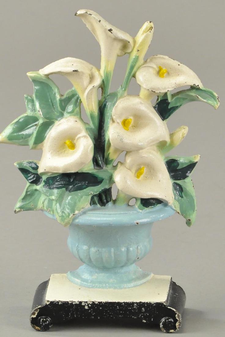 CALLALILLIES DOORSTOP: Hubley, "Made in USA, 343," depicts elegant white cone shaped flowers with deep green colored foliage in a brilliant blue vase on base. 7 1/8" h.