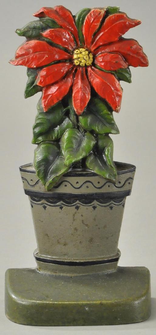 POINSETTIA DOORSTOP: cjo Judd, depiction of single poinsettia flower in 2 toned planter. Beautiful bright colors, great hand painted details to planter and great casting. 9 3/4" h