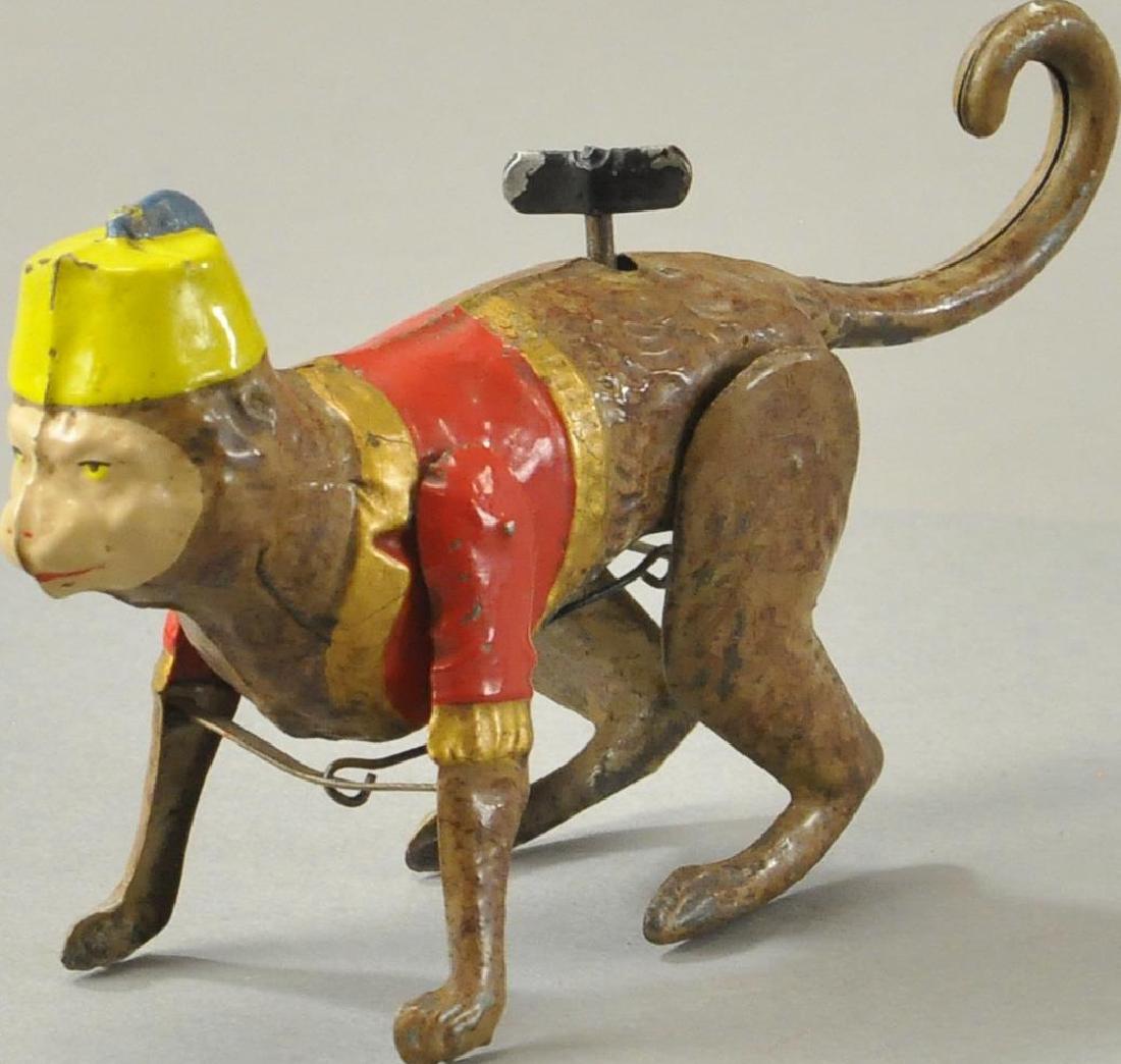 CRAWLING MONKEY WITH FEZ: Germany, hand painted tin monkey in crawling pose, dressed in vest and fez cap, wind up at back causes a hopping like crawling motion. 6"l.