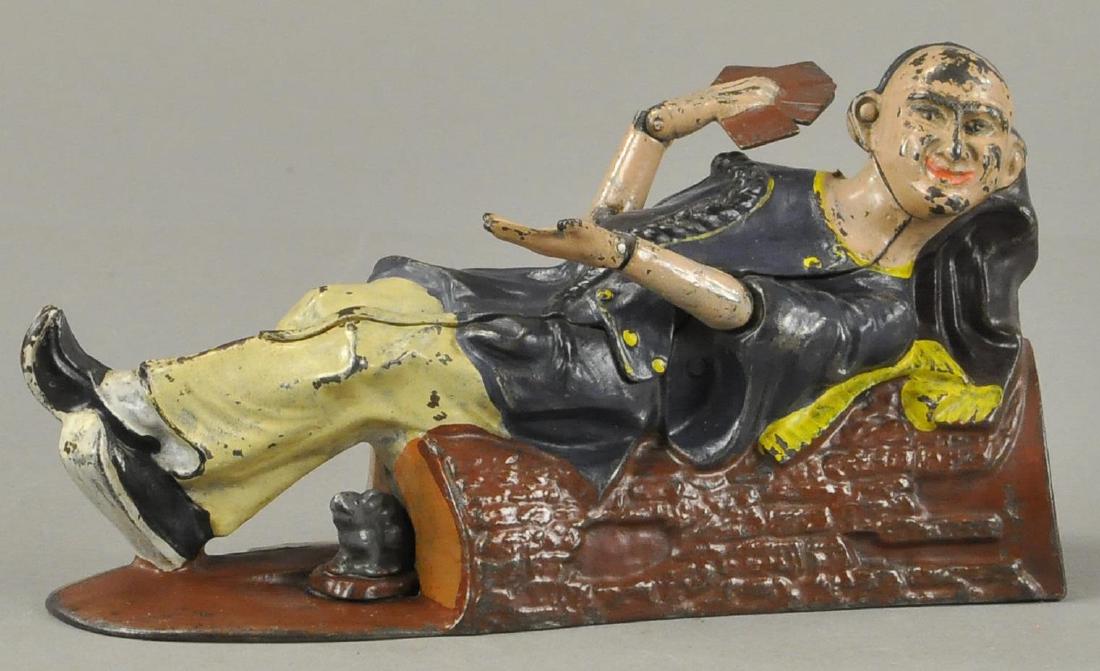 RECLINING CHINAMAN MECHANICAL BANK: A very involved motion J. & E. Stevens Co piece, c. 1882, placing coin in his pocket and pressing lever allows him to show his four aces and waive at the depositor.