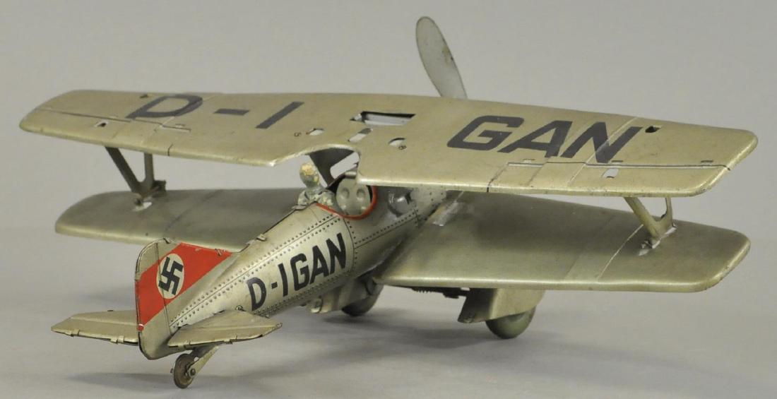 NAZI GERMAN MILITARY BI-PLANE: Clockwork litho bi-plane marked "D-IGAN" on wings and tail, detailed litho rivets along air frame and detailed engine exhaust behind propeller, has swastika on tail and removable pilot in cockpit. 10"