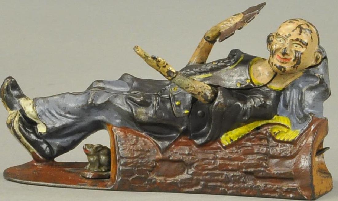 RECLINING CHINAMAN MECHANICAL BANK: 1060. RECLINING CHINAMAN MECHANICAL BANK | A clever action bank, J. & E. Stevens Co., c. 1882, place coin in his pocket, pressing lever allows him to show his four aces and waive at the depositor.