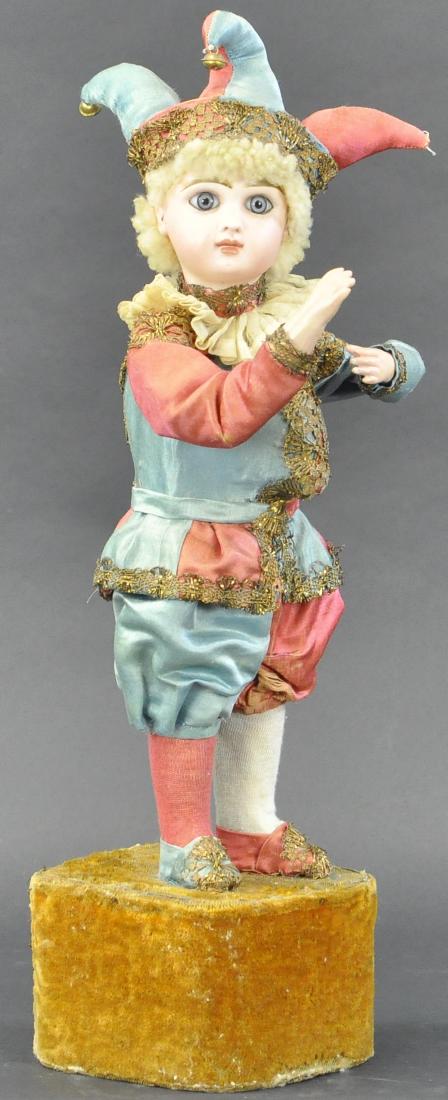 FRENCH MUSICIAL MECHANICAL WITH JUMEAU HEAD: 182. FRENCH MUSICIAL MECHANICAL WITH JUMEAU HEAD | Boy dressed as "Polichinelle" with protruding hump on back, dressed in alternation squares of dark rose and turquoise silk with gold braid trim, musi
