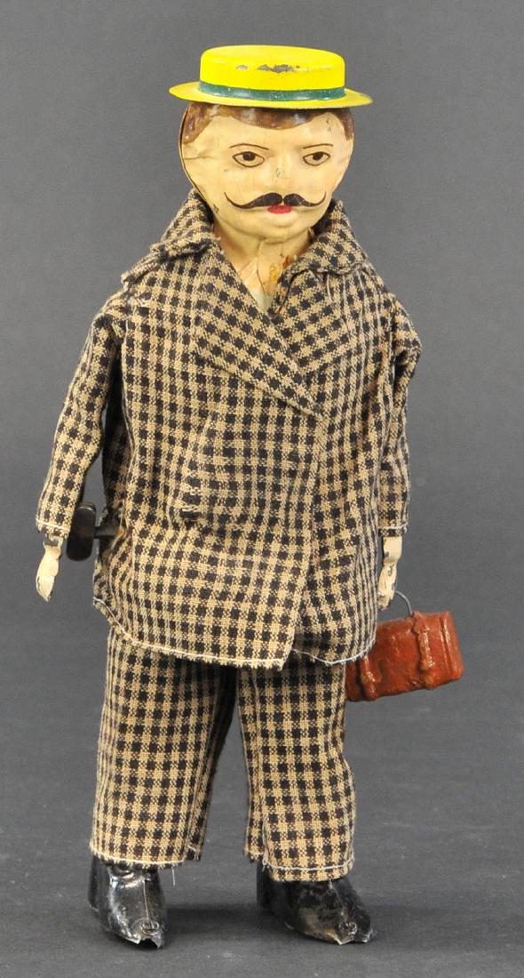 GERMAN MAN WITH SUITCASE: 256. GERMAN MAN WITH SUITCASE | c. 1910, Hard to find German made clockwork toy attributed to Gunthermann, tin litho and cloth, depicting a dapper gentleman dressed in a black and gold hounds tooth su