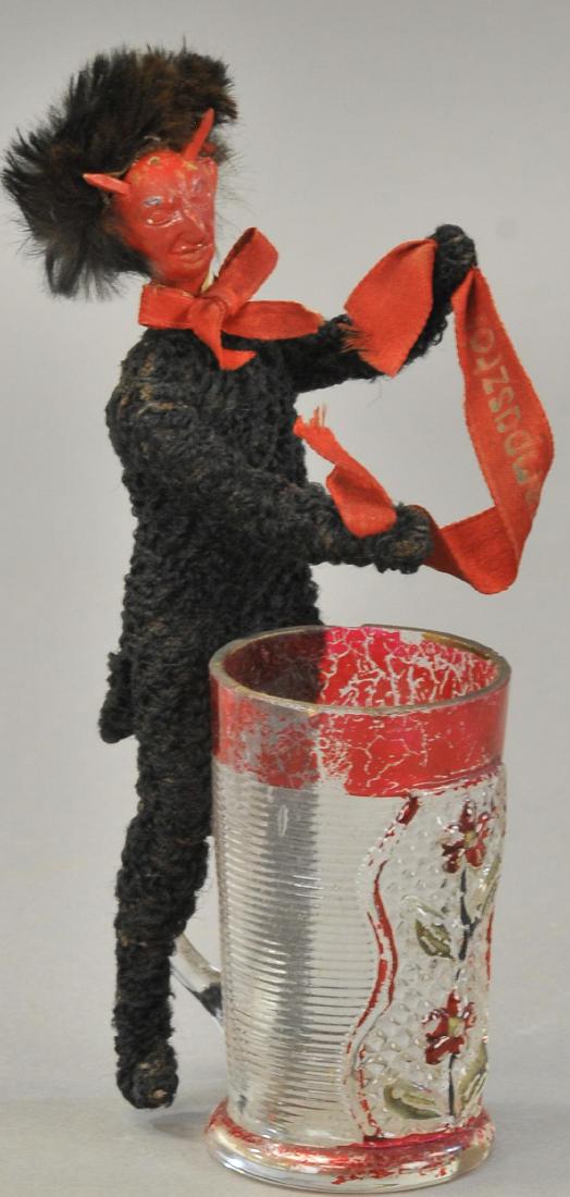 EVIL LOOKING KRAMPUS: 2252. EVIL LOOKING KRAMPUS | Eastern Europe Krampus with ruby flashed glass basket to put bad children into, composition head with cloth on wire body. 7.5" h.