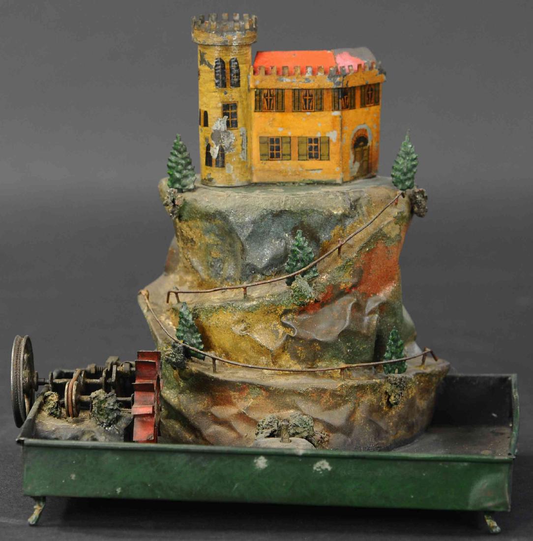 CASTLE W/ MOAT STEAM ACCESSORY: 500. CASTLE W/ MOAT STEAM ACCESSORY | Small castle sitting atop tinplate mountain, switchback pathway leads to top, fountain below squirts water when pulley wheel is driven by steam engine. | 10" h.
