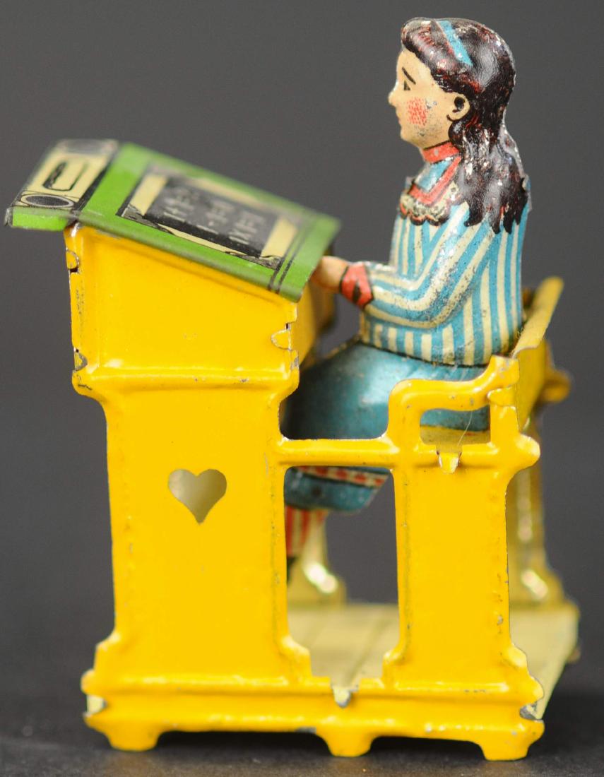 MEIER GIRL AT SCHOOL DESK PENNY TOY: 51. MEIER GIRL AT SCHOOL DESK PENNY TOY | Originally sold as a boy and girl figure seated. Mathematical equations appear on desk surface.