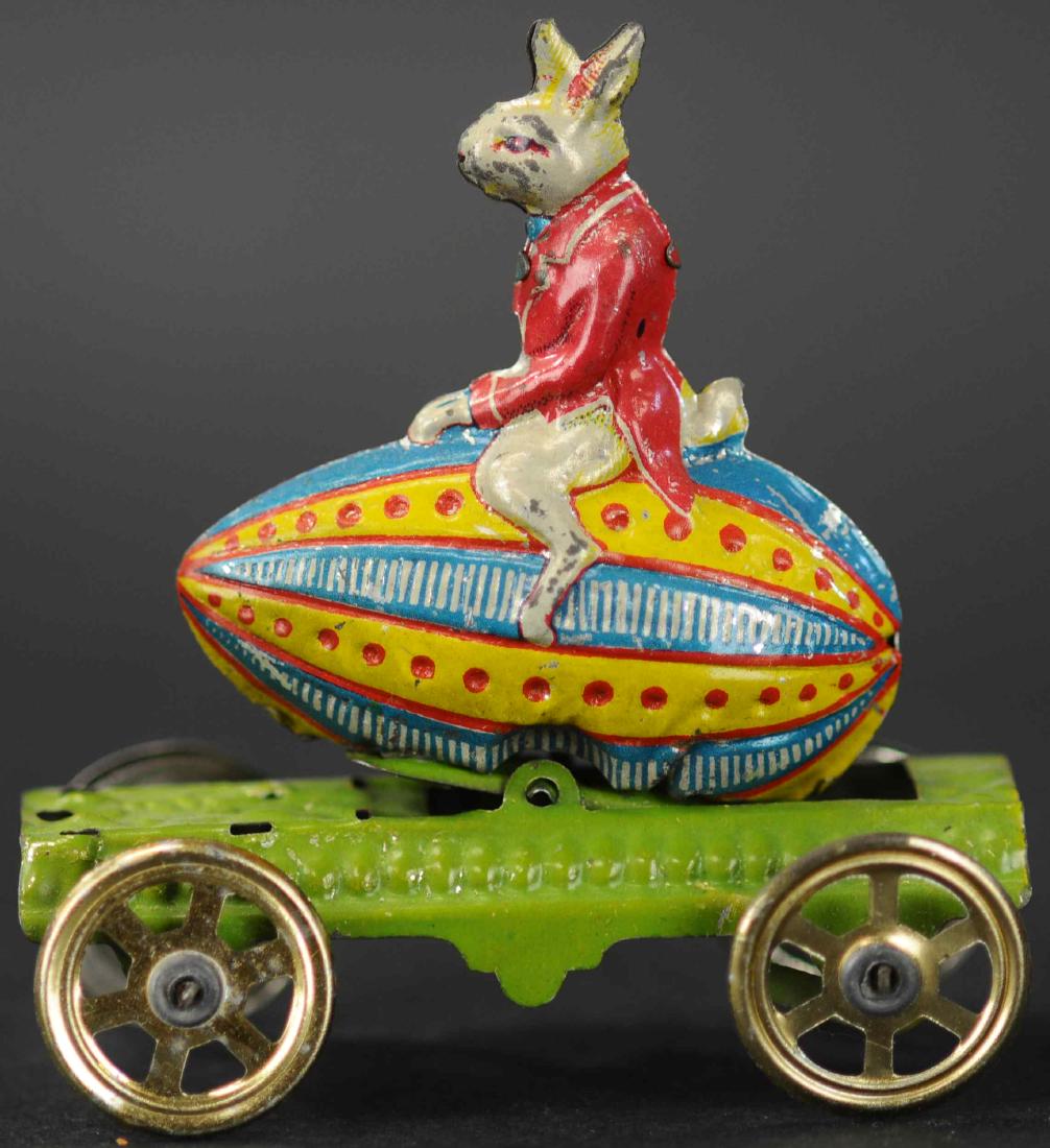 MEIER RABBIT ON EGG PENNY TOY: 110. MEIER RABBIT ON EGG PENNY TOY | Very rare, comical theme of well dressed Peter Rabbit seated on top of large decorated Easter egg, articulated axle causes the egg to rock.