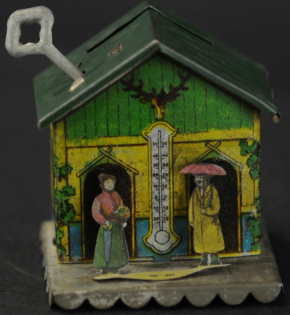 MONEY BOX PENNY TOY W/DIECUT FIGURES: 118. MONEY BOX PENNY TOY W/DIECUT FIGURES | Simple designed money box with coin slot in roof, dieut tin people figures are mounted at front to add a nice depth effect.