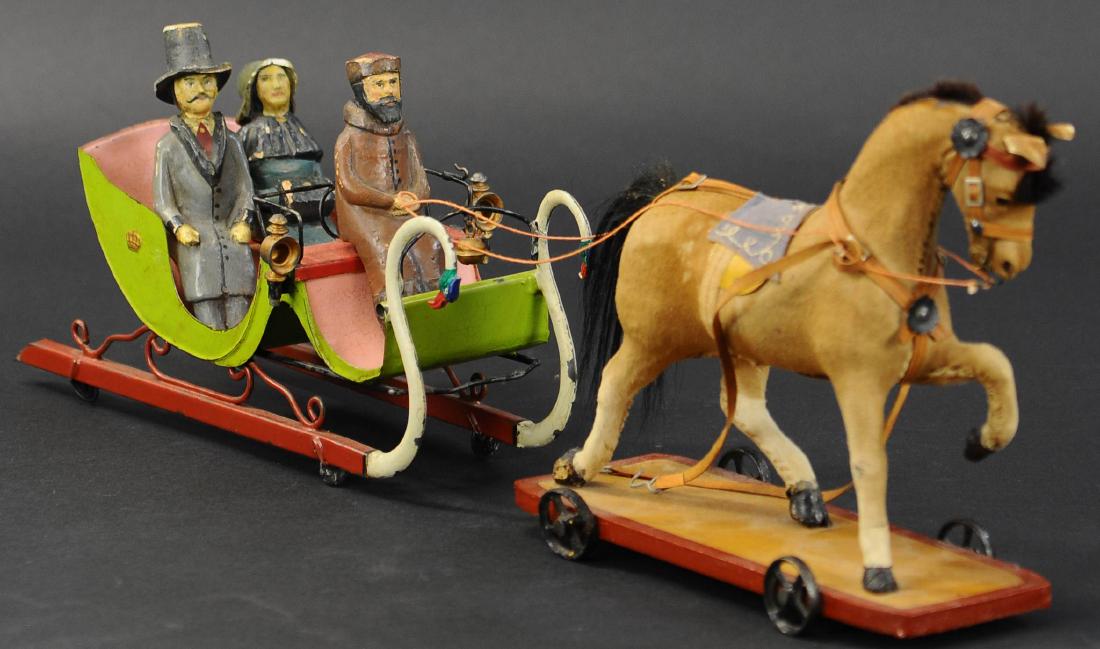 GERMAN TIN SNOW SLEIGH W/ FIGURES: 142. GERMAN TIN SNOW SLEIGH W/ FIGURES | Attributed to Rock & Graner, c. 1880. Hand-painted tin, on disc wheels, with 2 lamps and bell, 3 composition figures, length of the sleigh, with draught horse