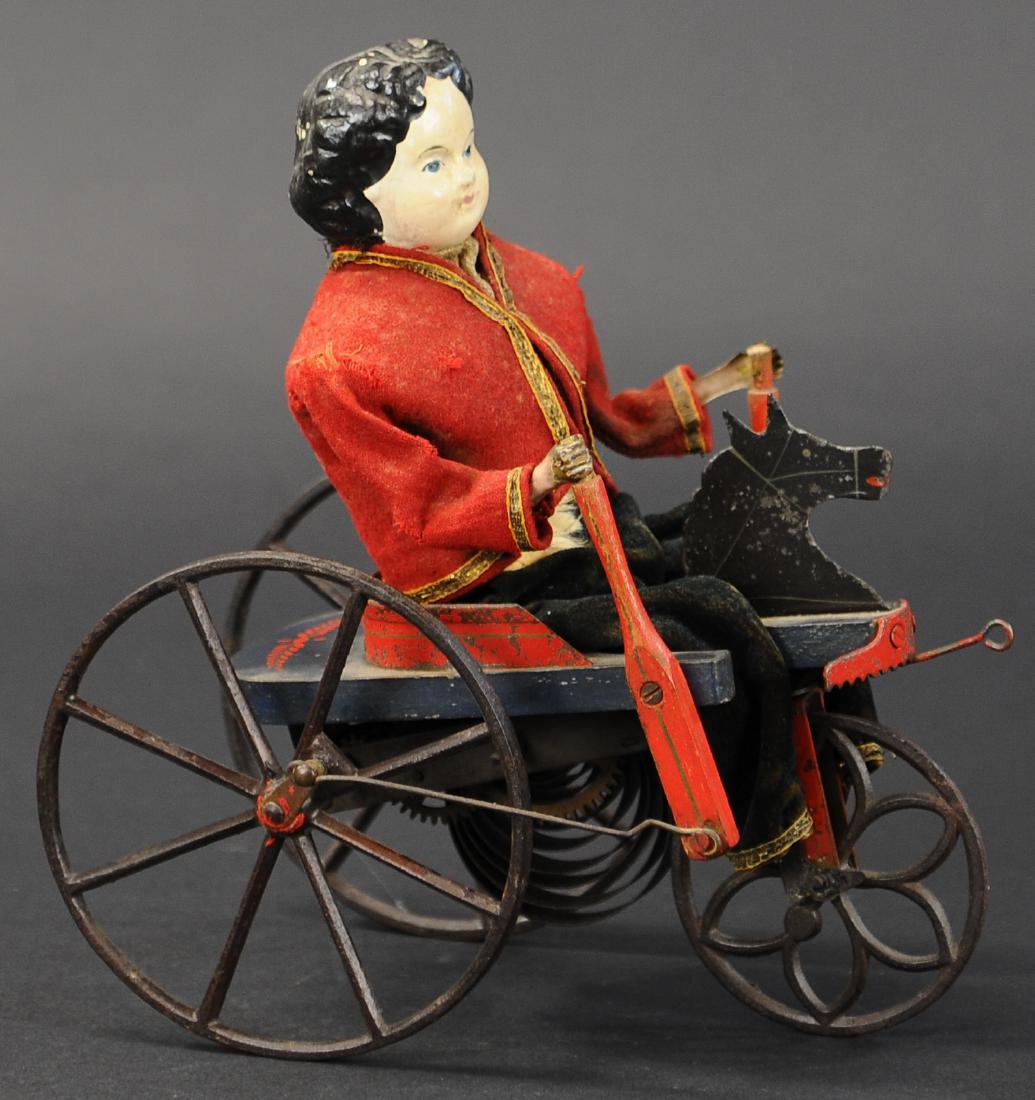 IVES TOY PERAMBULATOR: 184. IVES TOY PERAMBULATOR | c. 1873, an early and rare toy example, inventive piece depicts a young boy maneuvering his velocipede complete with wood handles, seemingly allowing forward motion as clo