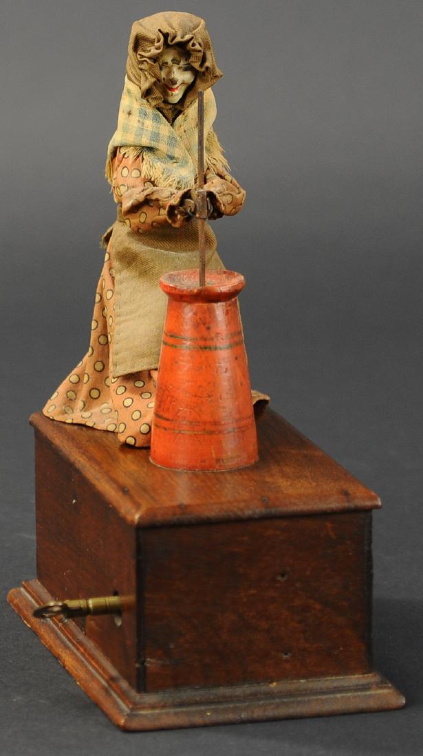 IVES "THE CHURNING TOY": 187. IVES "THE CHURNING TOY" | Patented by Albert H. Dean, 1874, a very desirable toy as few examples are known to exist. Clockwork mechanism is concealed in the wood base. The up and down movement of