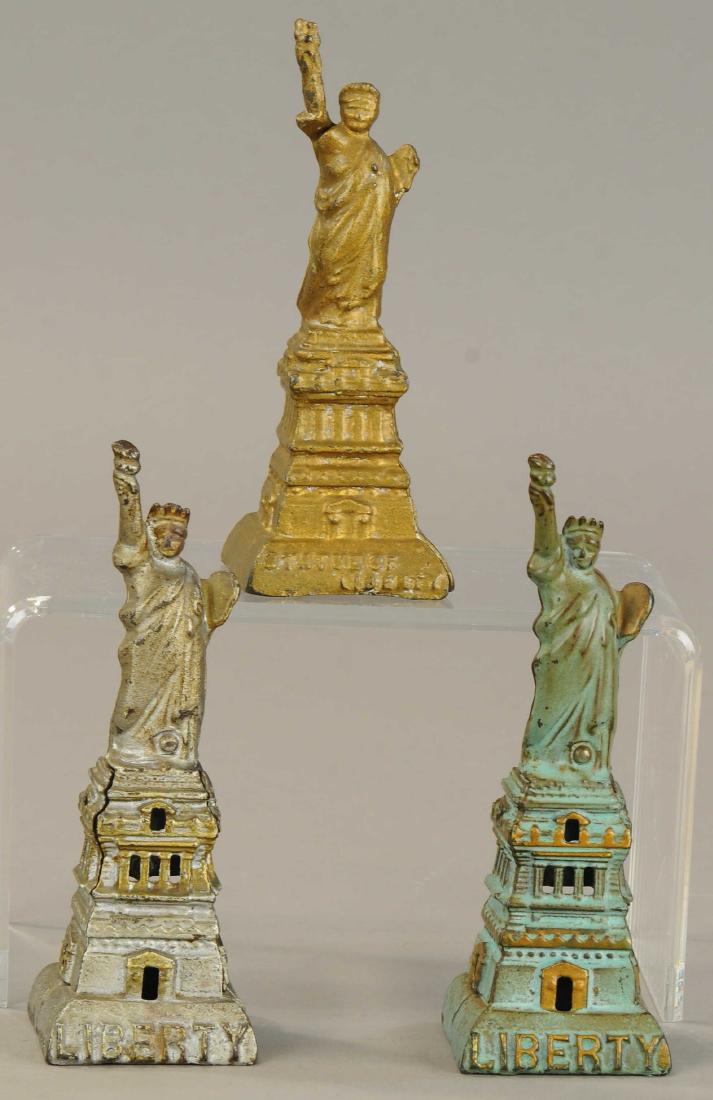 THREE STATUE OF LIBERTY STILL BANKS: 259. THREE STATUE OF LIBERTY STILL BANKS | Two painted are Kenton, small gold is A.C. Williams. | 6.5" h. | (Exc. Cond,) | $400 - $600