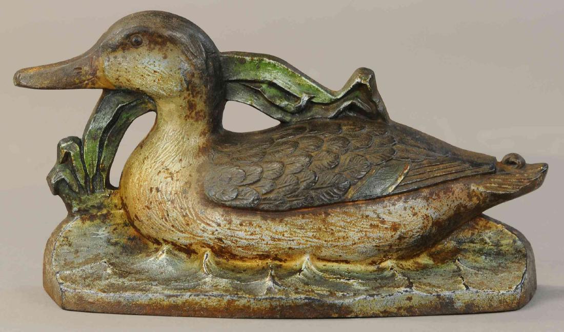MALLARD ON WATER DOORSTOP: 380. MALLARD ON WATER DOORSTOP | Cast iron, depicts mallard hen swimming with reeds in the background. | 11"l. | (VG-Exc. Cond.) | $1,000 - $1,500