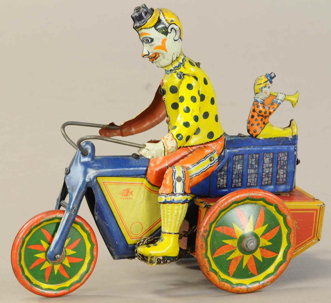FISCHER CLOWNS ON MOTORCYCLE: 1051. FISCHER CLOWNS ON MOTORCYCLE | Comical German bike features a tiny trumpet blowing clown seated at rear of bike, chain driven motor does wheelies as it moves. | 8" l. | Very minor crease and tou