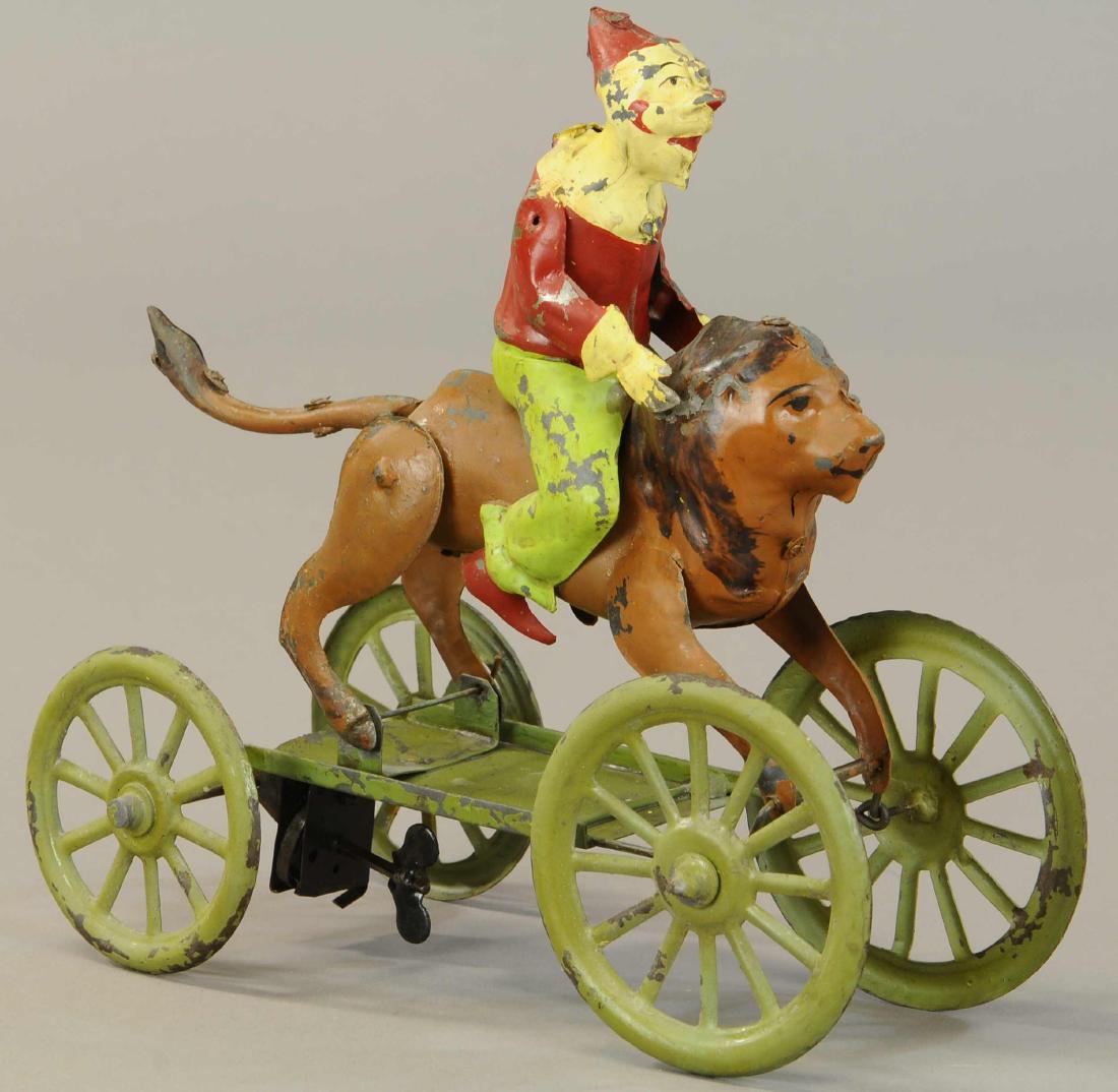 GUNTHERMANN CLOWN RIDING LION PLINK PLANK TOY: 1081. GUNTHERMANN CLOWN RIDING LION PLINK PLANK TOY | Front axle is articulated to simulate galloping motion of lion as he sprints. | 8.75"h. | Professionally Restored. | $600 - $900