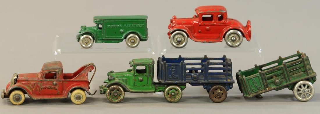 LOT OF FOUR CAST IRON VEHICLES: 1091. LOT OF FOUR CAST IRON VEHICLES | Plymouth arcade wrecker, moving storage bus, Coupe, and Semi-stake truck w/trailers. | 7" l. | All Original Condition. | $250 - $500