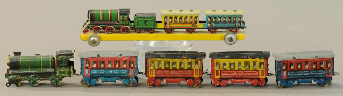 GROUP OF TRAIN PENNY TOYS: 76. GROUP OF TRAIN PENNY TOYS | 5.5" h. | Larger locomotive has one set of wheels missing, otherwise all in Original Condition. | $150 - $300
