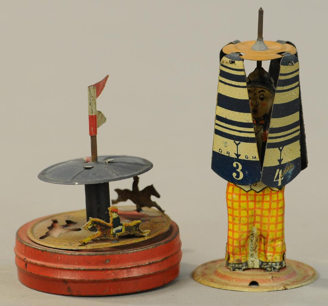 CARROUSEL PENNY TOY W/ SPINNING UMBRELLA MAN: 112. CARROUSEL PENNY TOY W/ SPINNING UMBRELLA MAN | Rare carrousel toy has one horseback figure missing, one figure present but detached, and one properly attached. | 4.5" h. | As noted, otherwise wor