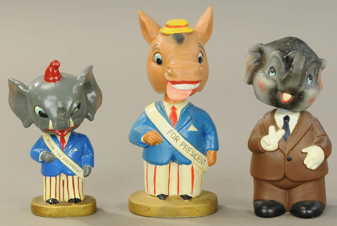 THREE POLITICAL BOBBLEHEADS: 176. THREE POLITICAL BOBBLEHEADS | Republican Elephant, two Democrat Donkeys. | 6" - 7.5' h. | Elephant in brown suit has chip repaired on side of head, Donkey has small crack on face, other in All Or