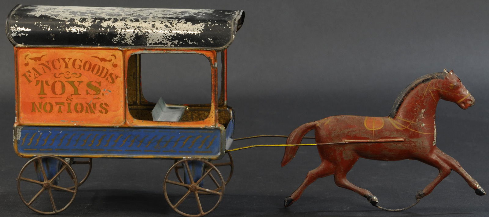 FALLOWS FANCY GOOD TOY WAGON: 318. FALLOWS FANCY GOOD TOY WAGON | c. 1870's, hand painted tin wagon w/ stenciling on sides, reads "Fancy Goods, Toys & Notions." | 19" length. | Roof flaking, otherwise in original (Very Good Condit