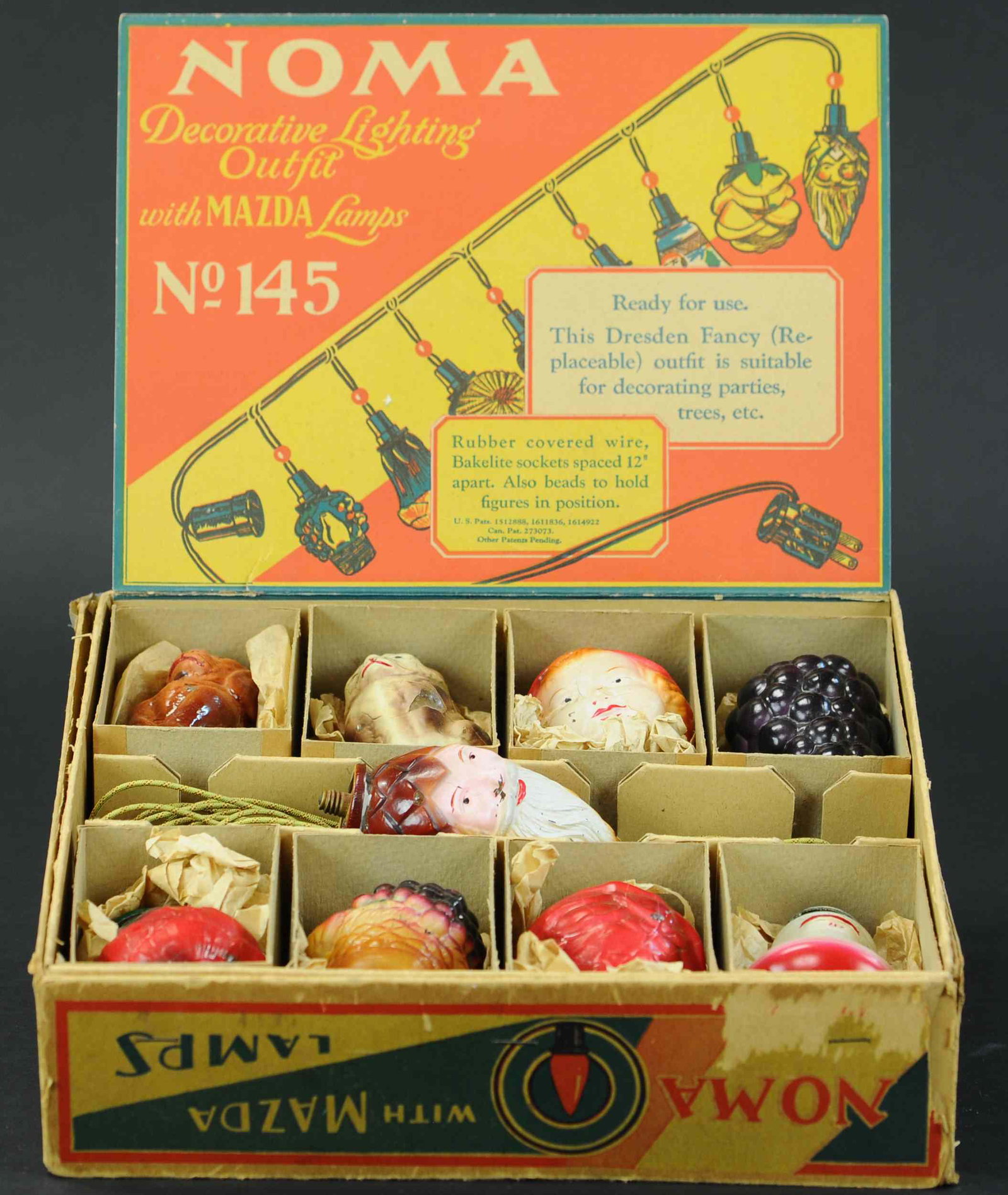 NOMA DECORATIVE LIGHTING OUTFIT: 609. NOMA DECORATIVE LIGHTING OUTFIT | Germany, Dresden Covers set, Noma Electric Co., 145 Circa 1932, set of eight plus a hard to find Santa Claus bulb. | 4" bulbs, box is 12" x 12". | Top ring of Sa