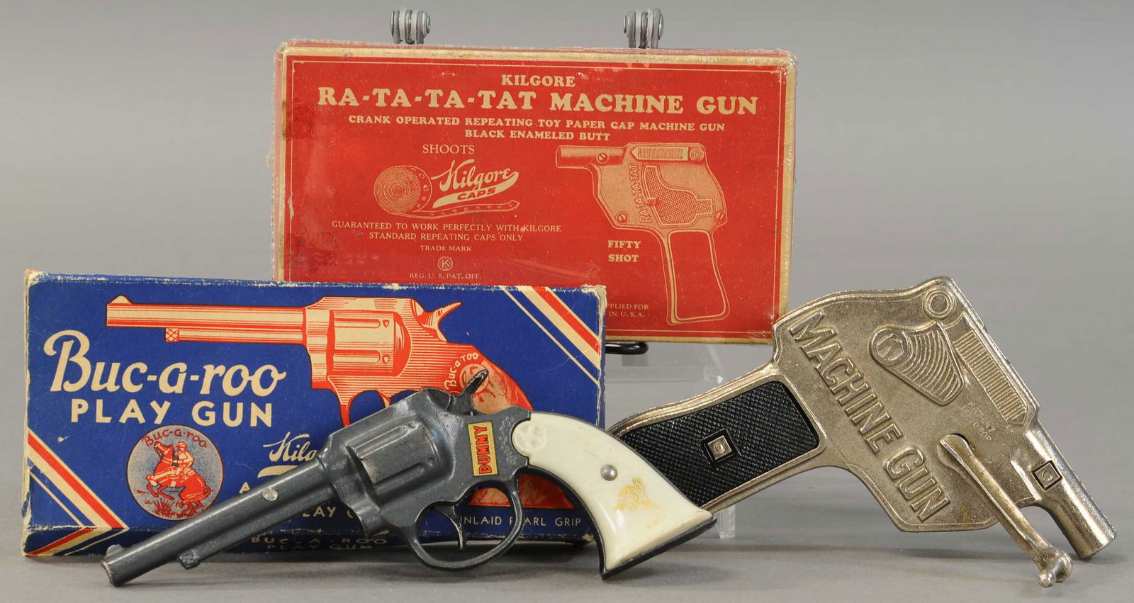 TWO BOXED KILGORE CAP GUNS: 435. TWO BOXED KILGORE CAP GUNS | Lot includes a machine gun and a Buc-a-roo 8" l. | Buc-a-roo box distressed and one end flap missing, possibly some tape on one edge of Rat-a-tat-tat box. Buc-a-roo g