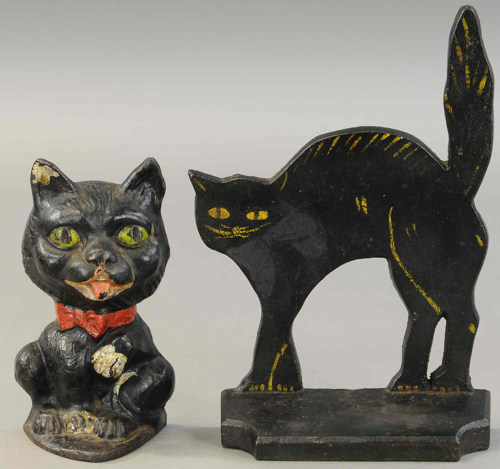 LOT OF TWO BLACK CAT DOORSTOPS: 457. LOT OF TWO BLACK CAT DOORSTOPS | Cat with paw up, Eastern Specialty Co., along with flat cat on base. 8" - 11" h. | (VG Cond.) | $200 - $400
