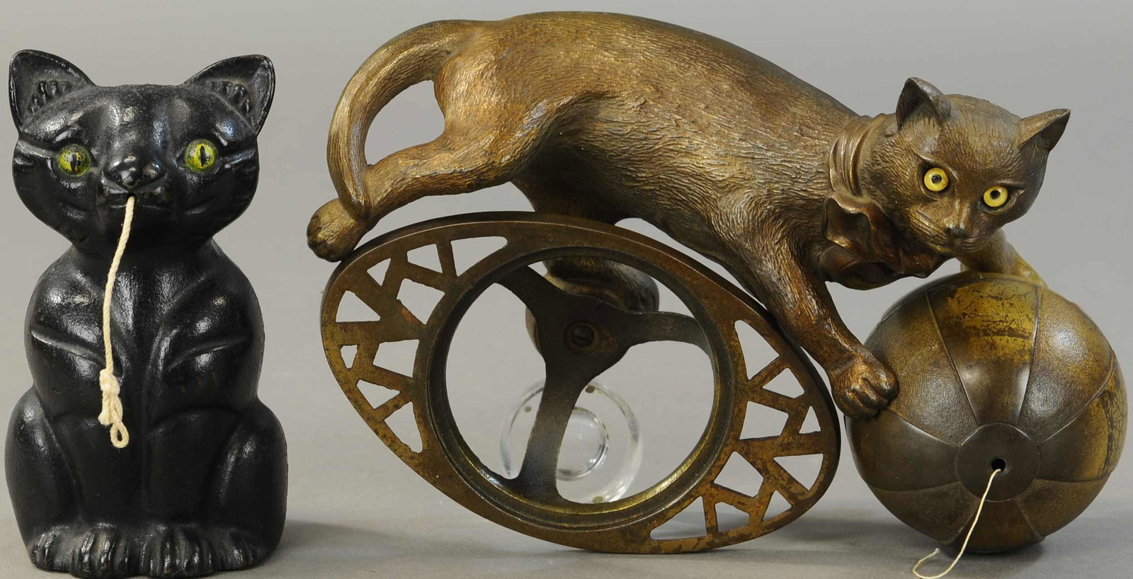 LOT OF TWO CAST IRON CAT STRINGHOLDERS: 486. LOT OF TWO CAST IRON CAT STRINGHOLDERS | Cat with glass eyes and ball that holds string, signed on the back, "From the Model of Harry Banks," and black cat string holder. 7" - 10" l. | Cat w/ball