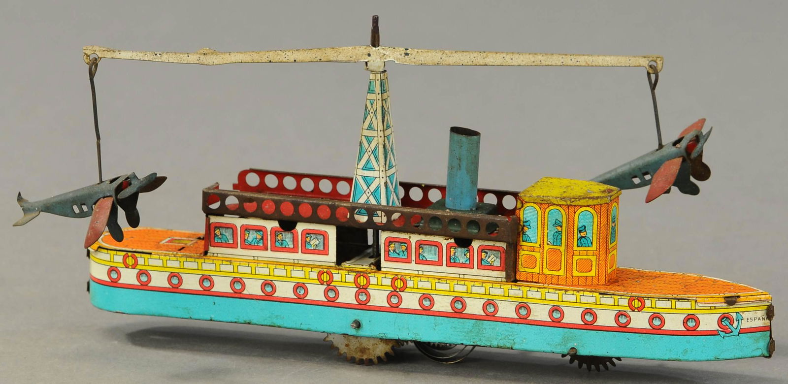 SPANISH OCEAN LINER W/ CIRCLING PLANES: 1052. SPANISH OCEAN LINER W/ CIRCLING PLANES | Unusual piece, marked Espana at front, colorful lithography throughout, wind up causes forward motion while airplanes rotate above. 9" l. | Has some oxid