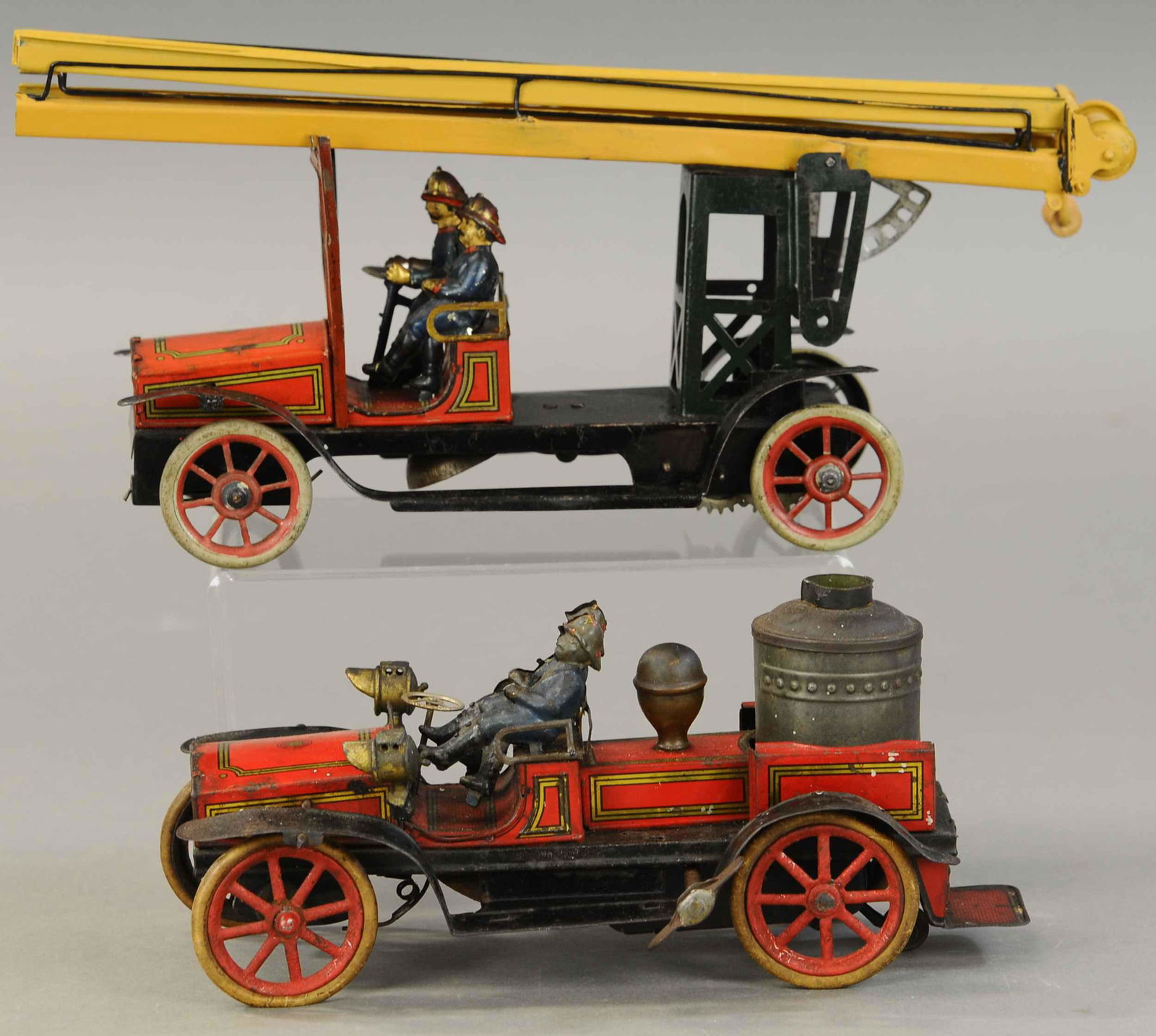 PAIR OF GUNTHERMANN FIRE TRUCKS: 1066. PAIR OF GUNTHERMANN FIRE TRUCKS | Germany, both with working wind-up motors. 13" l. | Pumper axle bell ringer inactive, ladders are repainted, otherwise working in (Exc. Cond.) | $1,000 - $1,500