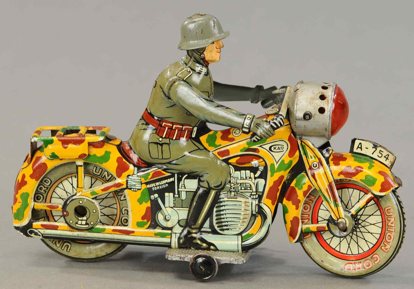 ARNOLD CAMOUFLAGED MILITARY CYCLE: 1222. ARNOLD CAMOUFLAGED MILITARY CYCLE | Side mounted wind-up drives cycle and sparks flint in searchlight. 7.5" l. | (Exc - Pristine Cond.) | $400 - $600