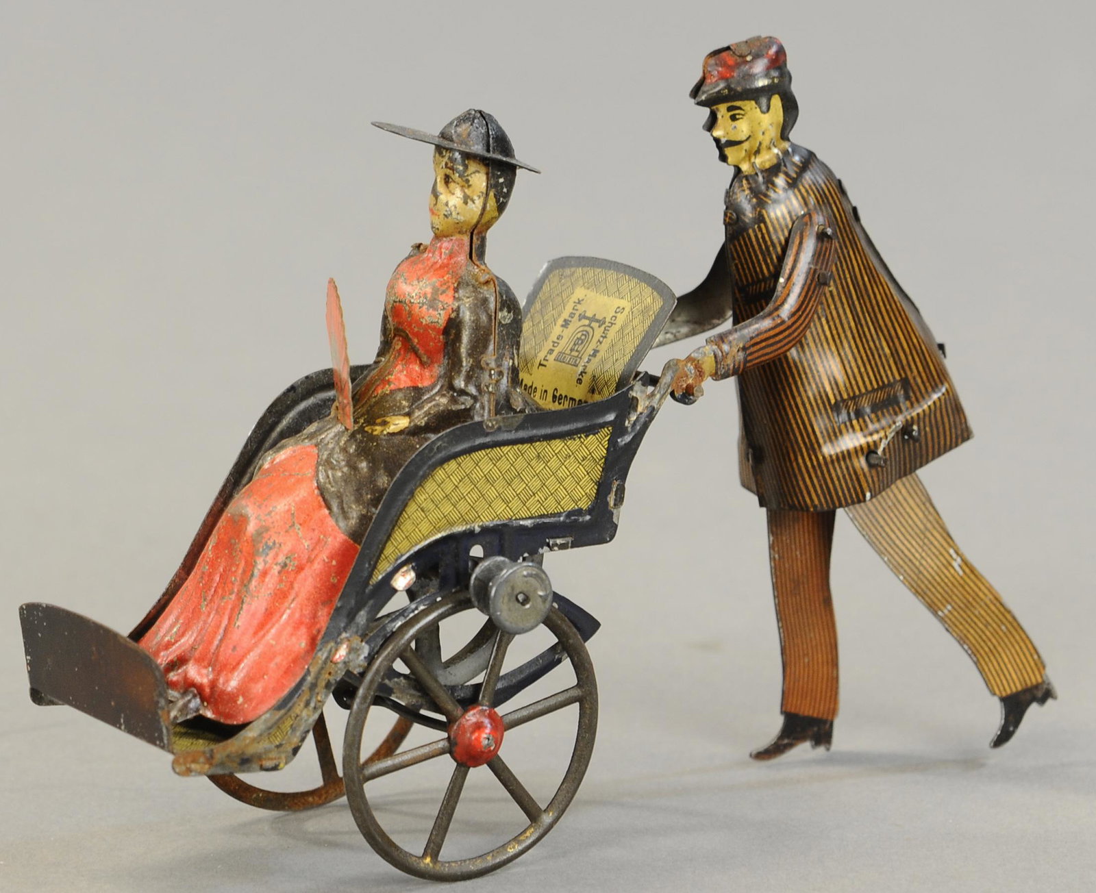 LEHMANN GOING TO THE FAIR: 1273. LEHMANN GOING TO THE FAIR | Early toy features a flywheel to cause walking/rolling motion, as the cart moves the woman fans herself. 5" h. | Woman's fan is replaced, otherwise in (Exc. Cond.) fo