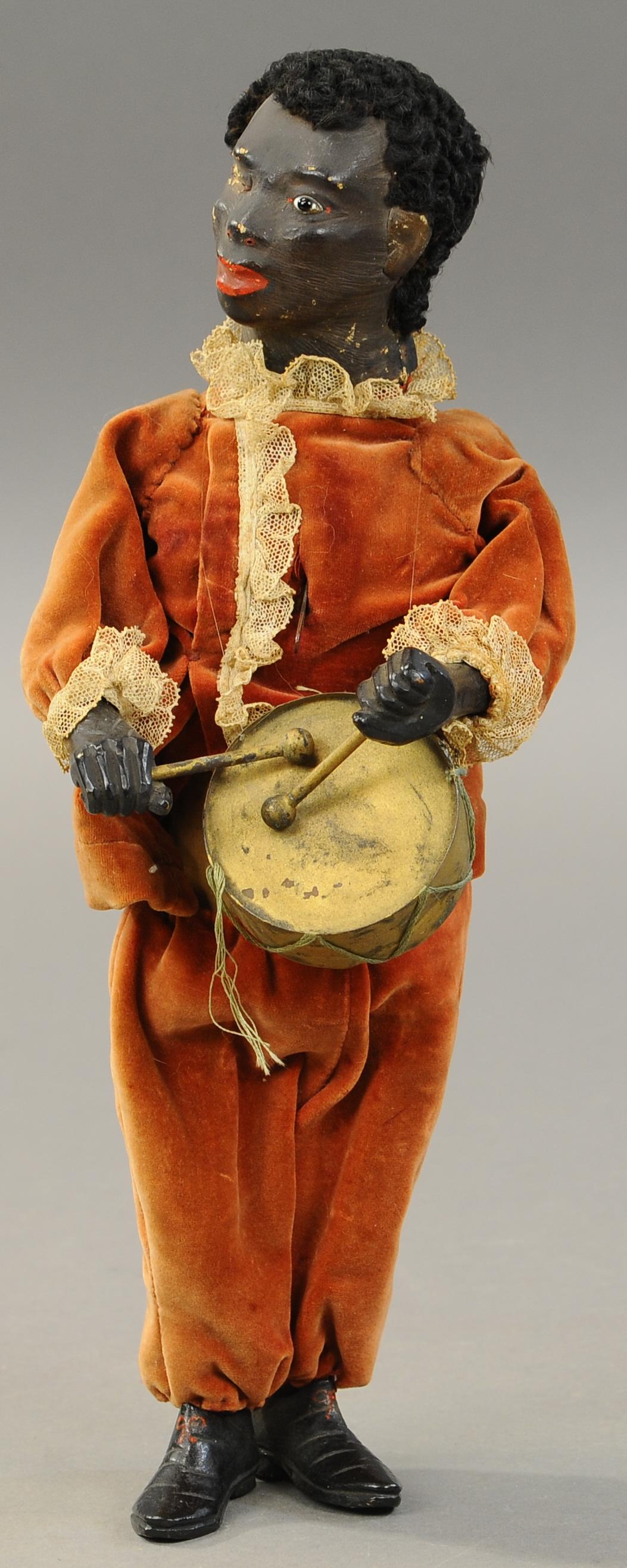 BLACK DRUMMER BOY MECHANICAL FIGURE: 1333. BLACK DRUMMER BOY MECHANICAL FIGURE | German, black man dressed in velvet and lace, when wound he plays the drum. 14" h . | Right eye is missing, overall (VG Cond.) | $600 - $900