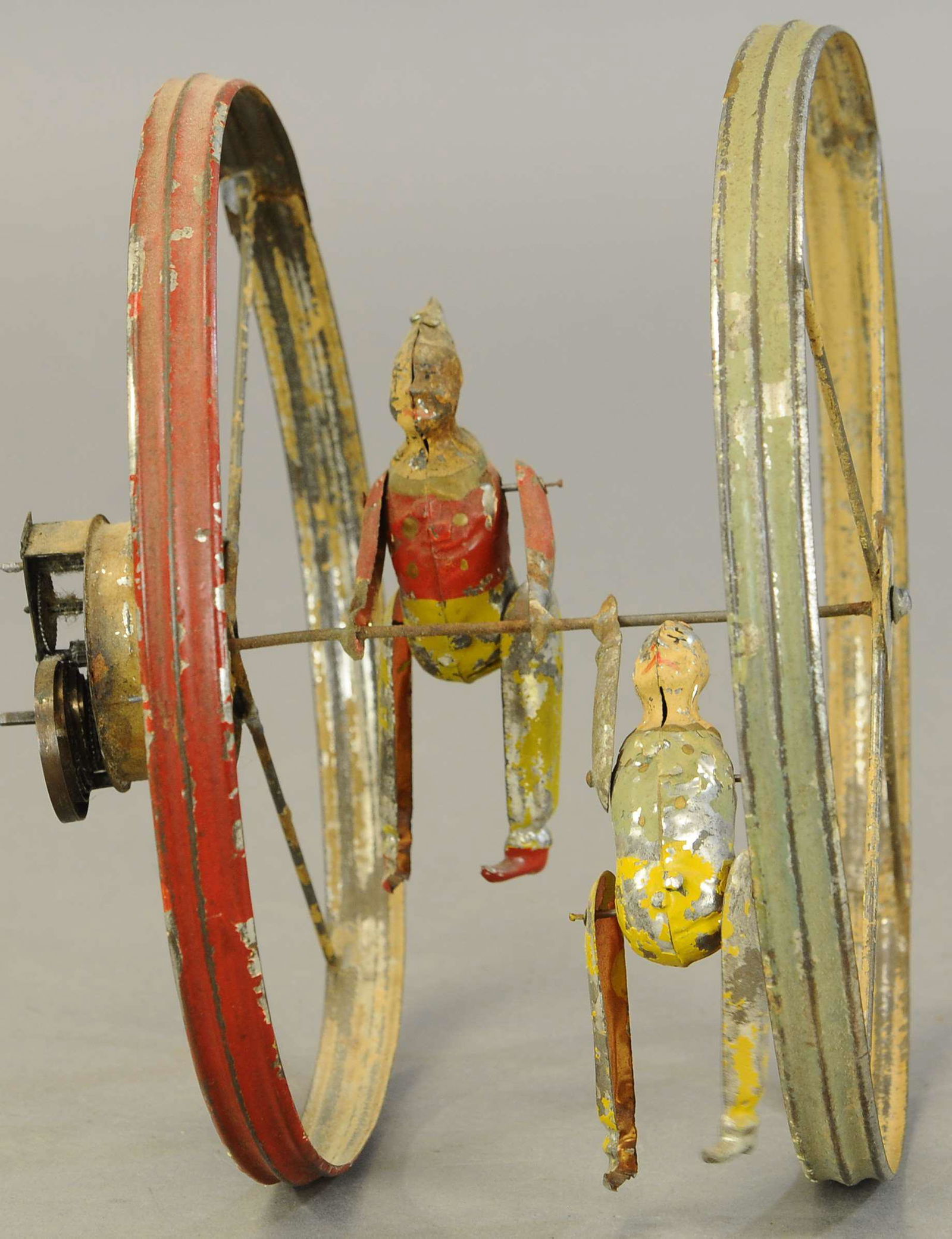 LARGE GERMAN CLOWNS HOOP TOY: 1367. LARGE GERMAN CLOWNS HOOP TOY | Germany, attributed to Gunthermann, hand painted, wind-up mech attached to side of hoop, causes rolling action as clowns perform flips over center cross bar. 10" d