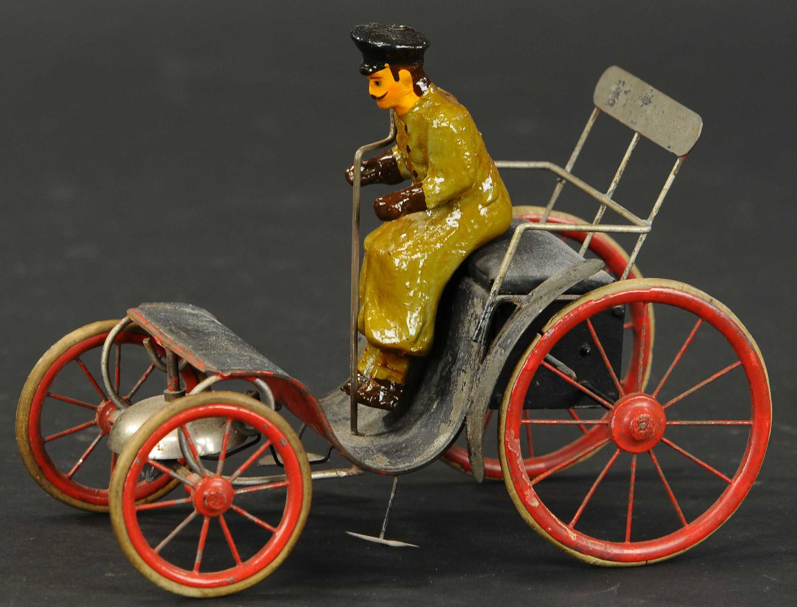 PRIMITIVE CLOCKWORK RUNABOUT: 2005. PRIMITIVE CLOCKWORK RUNABOUT | Attributed to Carette, wind-up concealed in rear, bell ringer mounted on front axle. 7.5" l. | Figure is replaced, reds are repainted, (Good Condition) | $500 - $7