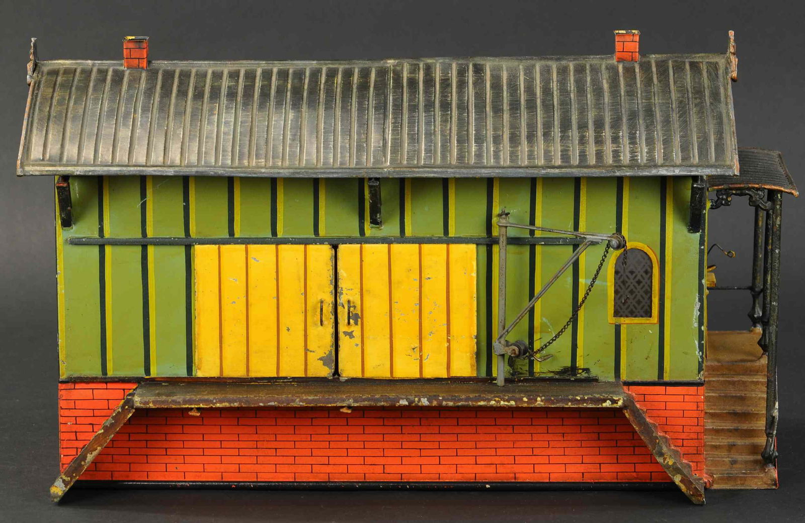 MARKLIN GAUGE III FREIGHT STATION: 2121. MARKLIN GAUGE III FREIGHT STATION | Hand painted, gauge 3, circa 1900, features cranes on both sides, working scale inside, rain gutter system and ornate castings on ends of roof, railings above