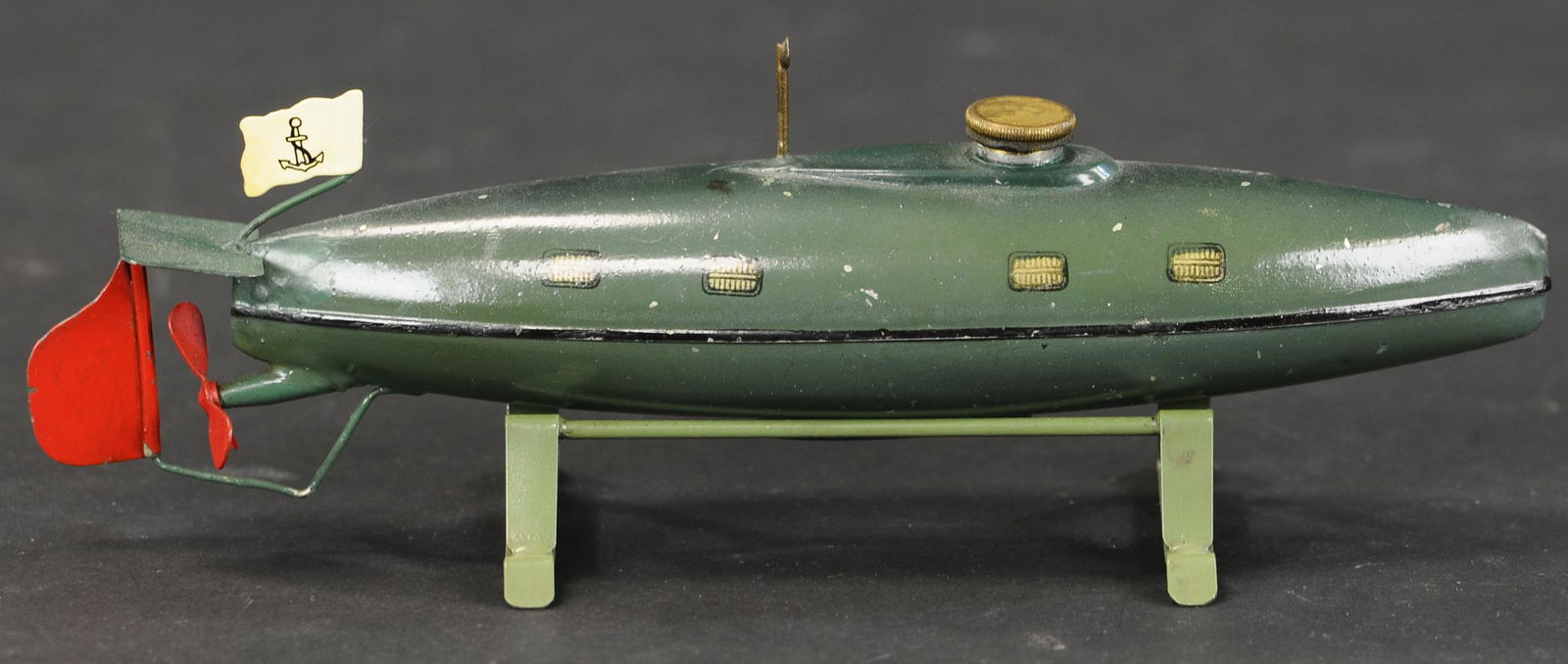 SMALL MARKLIN SUBMARINE: 2164. SMALL MARKLIN SUBMARINE | Wind-up, cute size, stand is replaced. 8.75" l. | Periscope, rudder, tailfin and flag re-attached and touched up accordingly, otherwise (Excellent Condition) | $700 - $