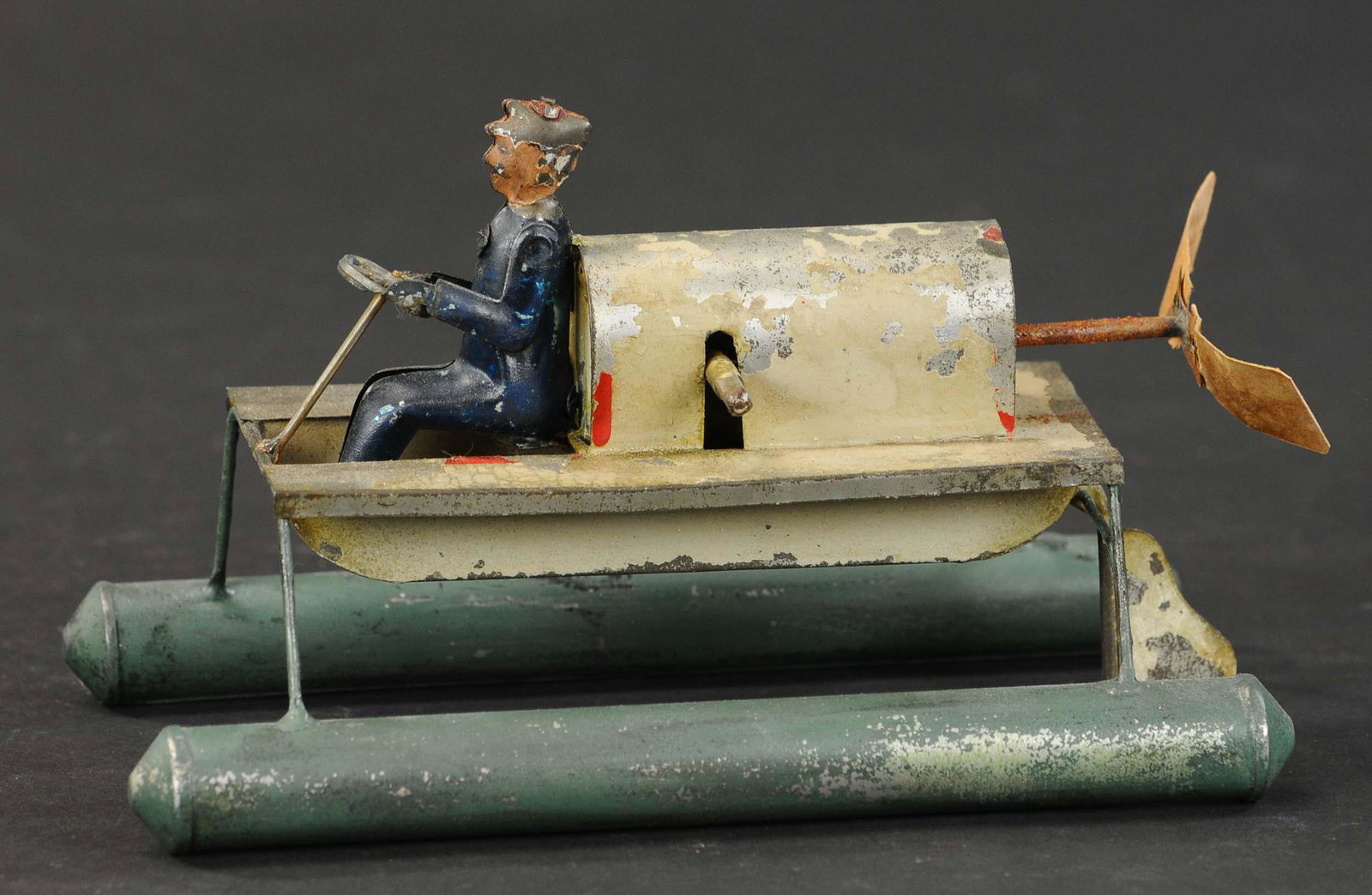 PLANK SPEEDBOAT ON PONTOONS: 2181. PLANK SPEEDBOAT ON PONTOONS | Wind-up. 7.5" l. | Driver figure and pontoons are repainted, working in otherwise (Very Good Condition) | $500 - $750 | Provenance: Sam Downey Collection.