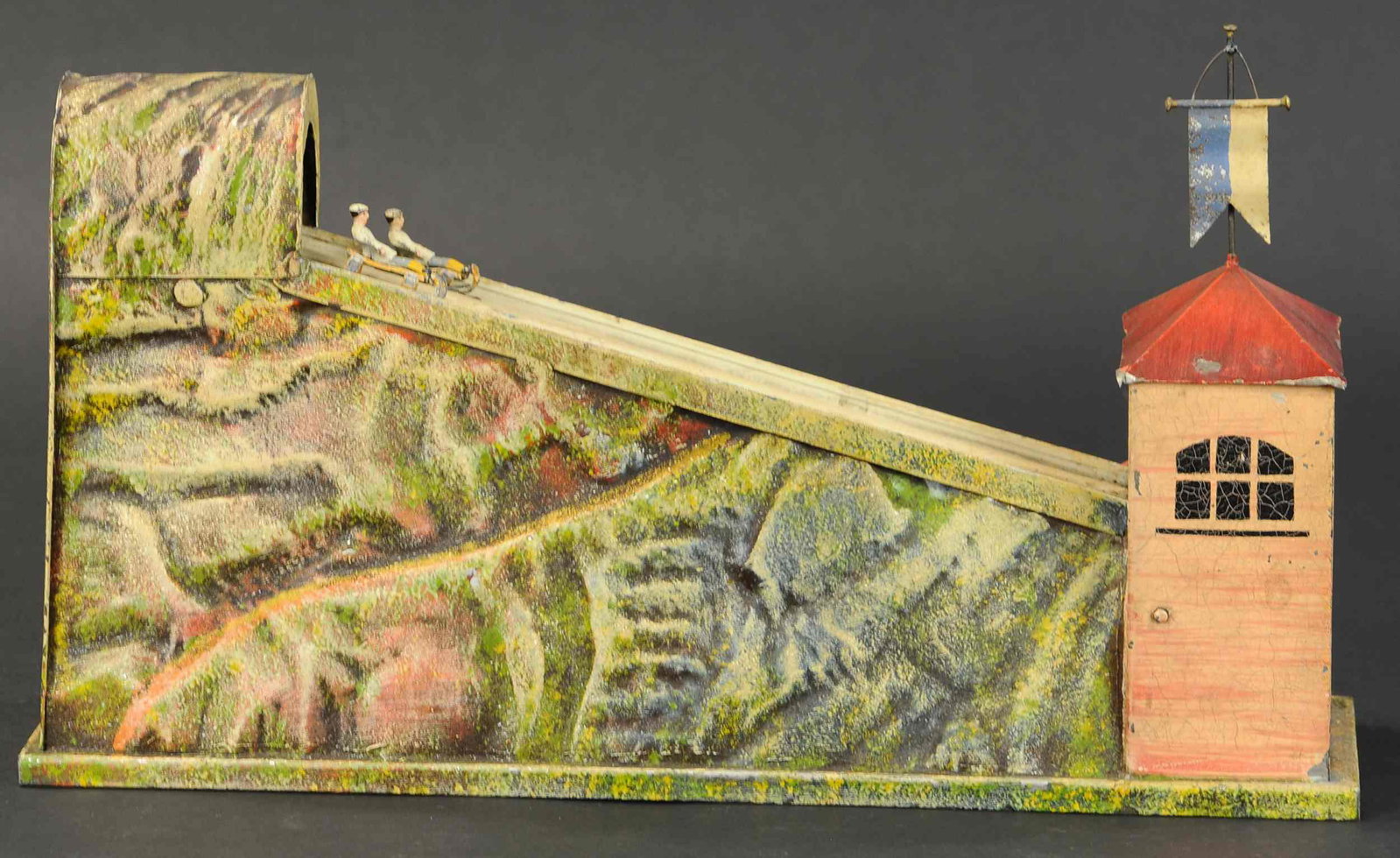 SLEDDING RACE STEAM TOY: 2206. SLEDDING RACE STEAM TOY | Embossed hand painted mountainscape featuring two children on sleds attached to a belt that is driven by a steam pulley wheel. 17" l. | All Original in (Excellent Condi