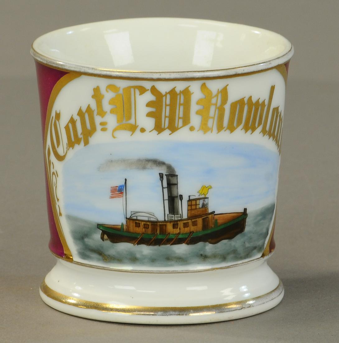 AMERICAN TUG BOAT OCCUPATIONAL SHAVING MUG: 2446. AMERICAN TUG BOAT OCCUPATIONAL SHAVING MUG | A “Capt.” Mug. Shows flag and eagle. No damage- gold wear to rims - name full. | As Noted. | $300 - $500 | Provenance: Sam Downey Collection.