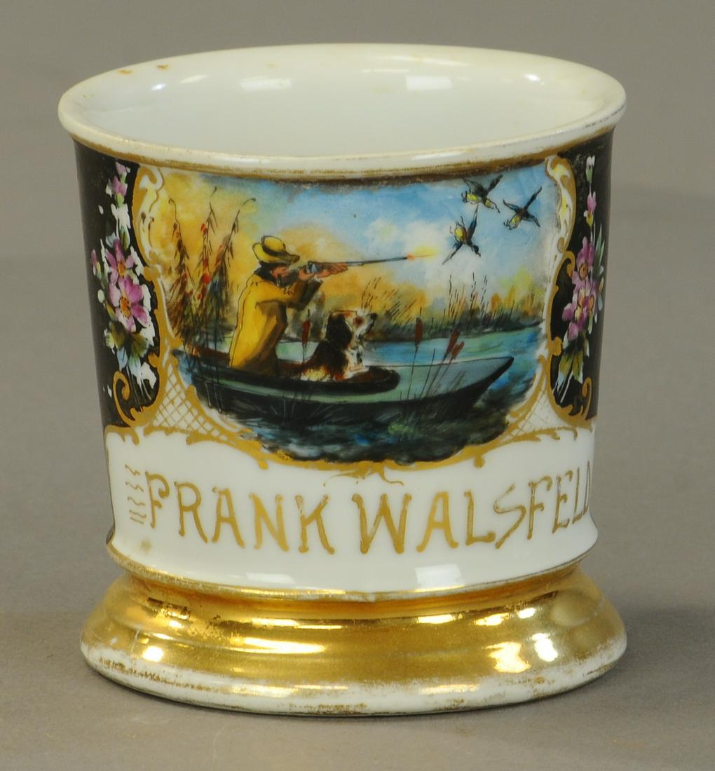 DUCK HUNTER W/ DOG OCCUPATIONAL SHAVING MUG: 2447. DUCK HUNTER W/ DOG OCCUPATIONAL SHAVING MUG | Man shooting at ducks , in boat with dog. Gold wear to rims no damage. | As Noted. | $200 - $400 | Provenance: Sam Downey Collection.