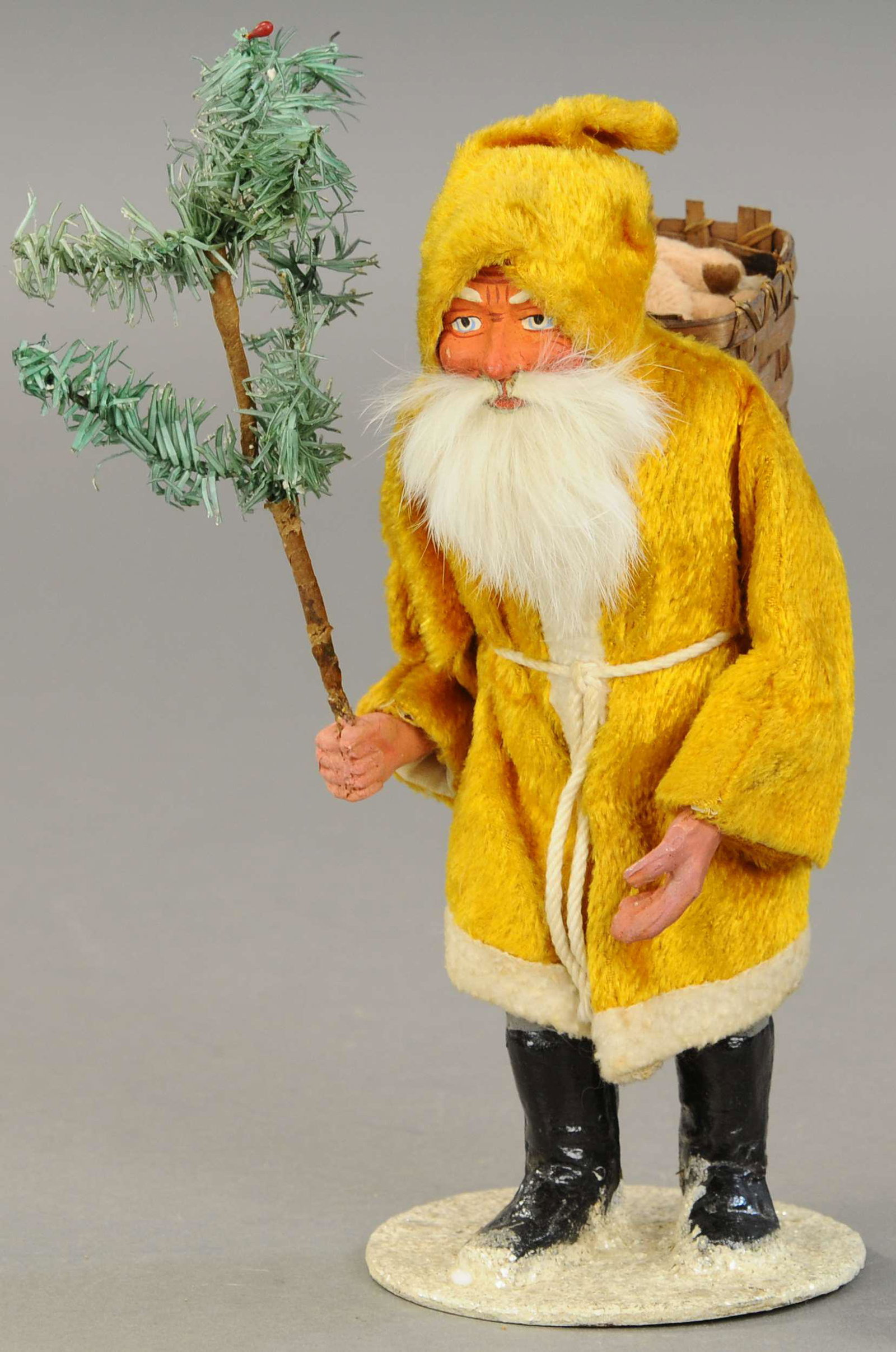 GOLDEN ROBE WOODCUTTER SANTA: 2503. GOLDEN ROBE WOODCUTTER SANTA | A forward leaning, walking Santa Claus of composition construction w/rabbit fur beard, feather tree in hand, toy basket on his back, wearing a fur-like golden robe