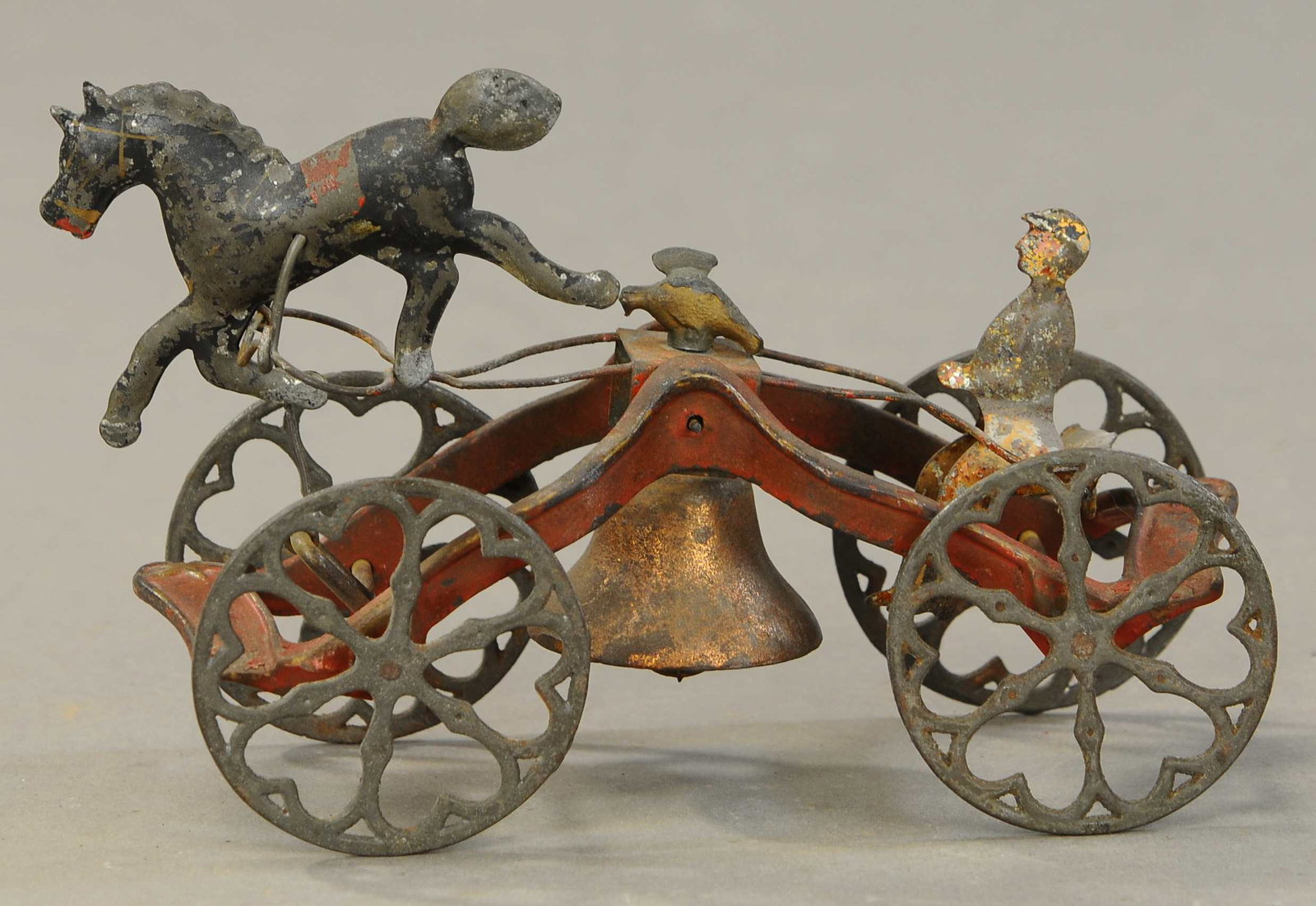 MAN RIDING CART WITH HORSE BELL TOY: 258. MAN RIDING CART WITH HORSE BELL TOY| Attributed to Gong Bell Co., cast iron open base painted in red with tin man in open seat and solo horse painted in black, articulated action allows back and 