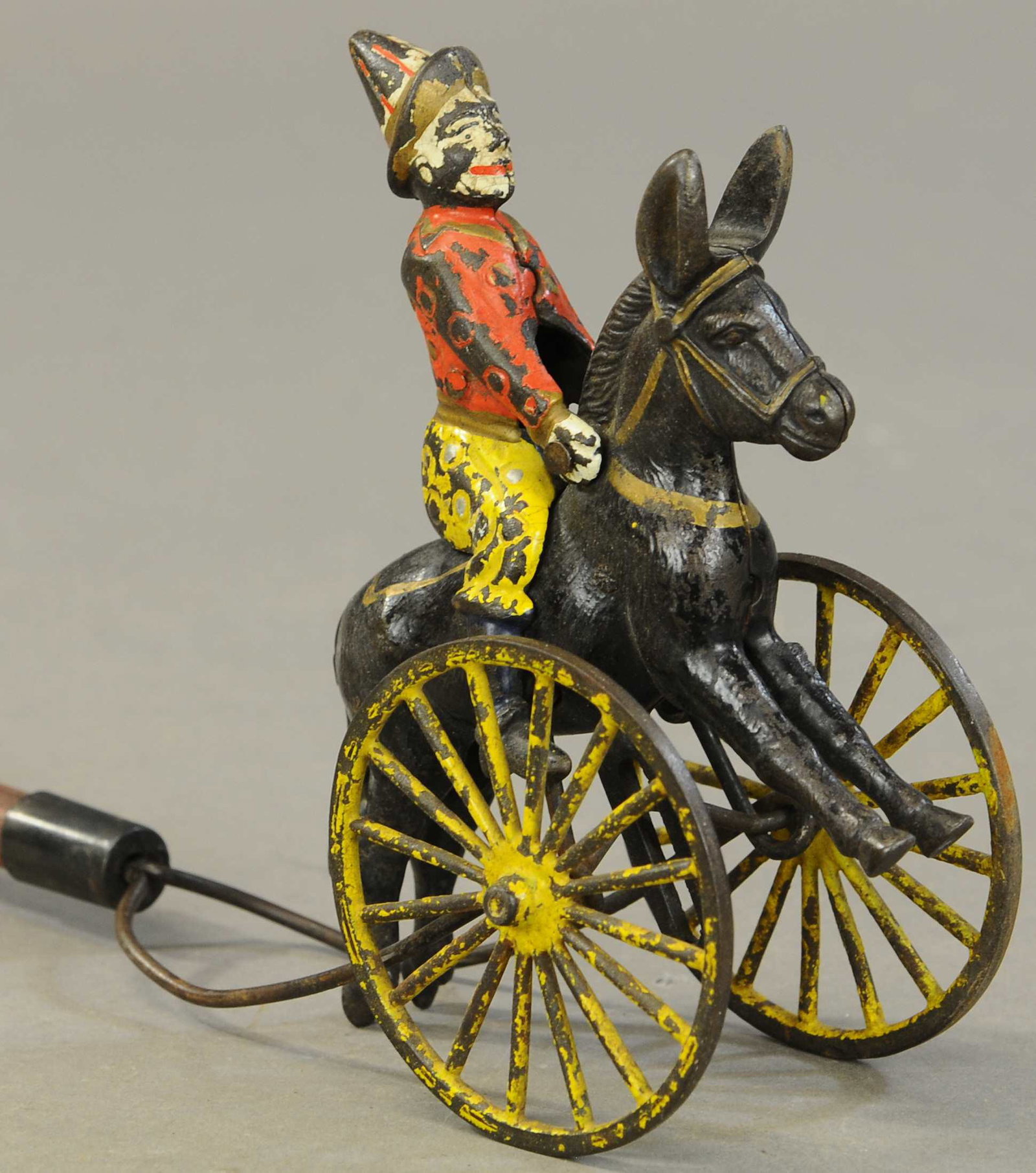 SCARCE CLOWN ON DONKEY PUSH TOY: 259. SCARCE CLOWN ON DONKEY PUSH TOY| Original wooden stick, nice casting.| 29" h.| All Original Condition.| $250 - $500